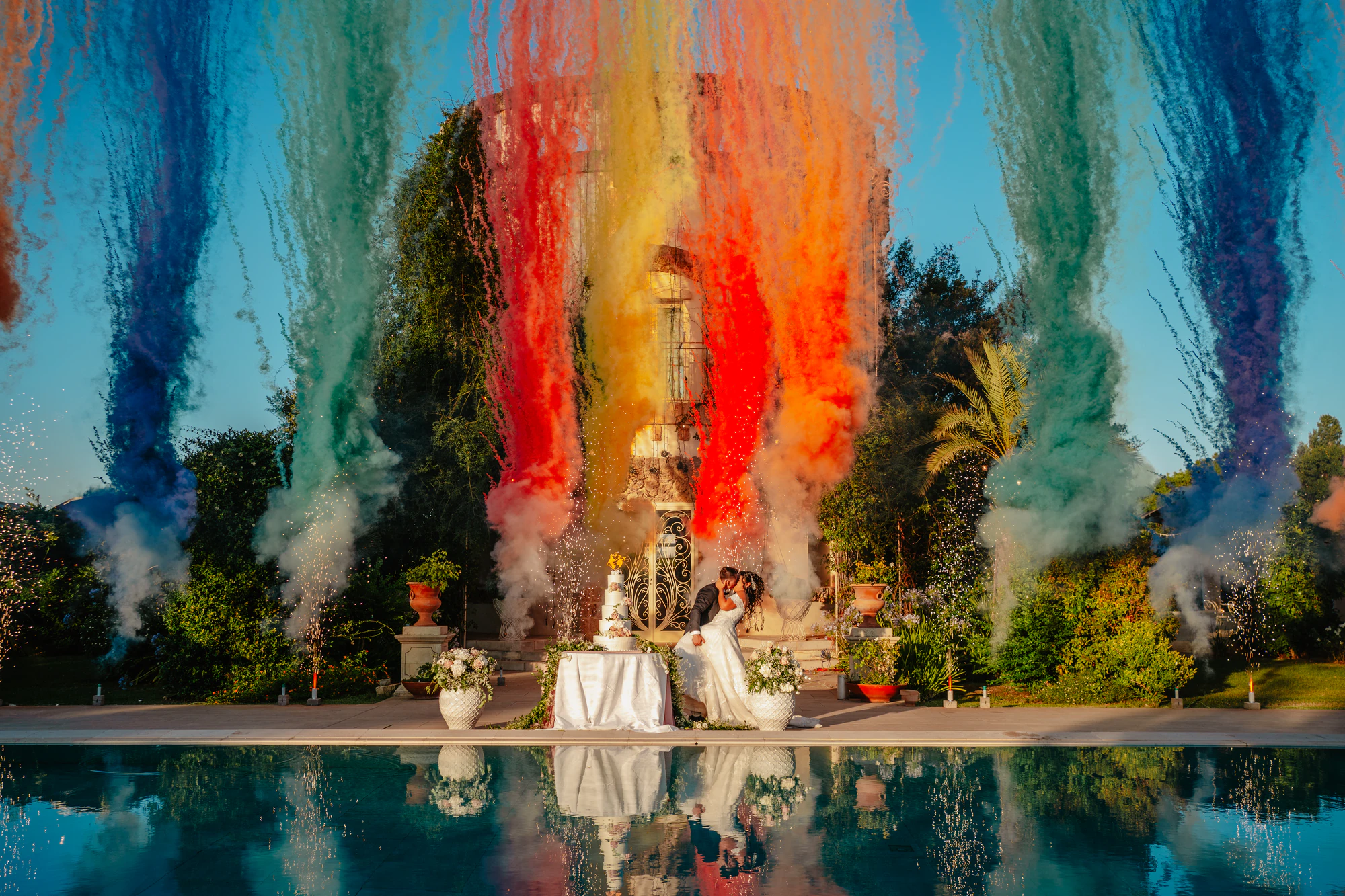 Cerimonia a bordo piscina con una smoke bomb arcobaleno che si riflette nell'acqua